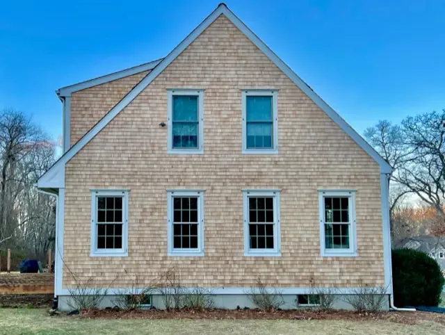 House side elevation with light cedar shingle siding and white-trimmed windows
